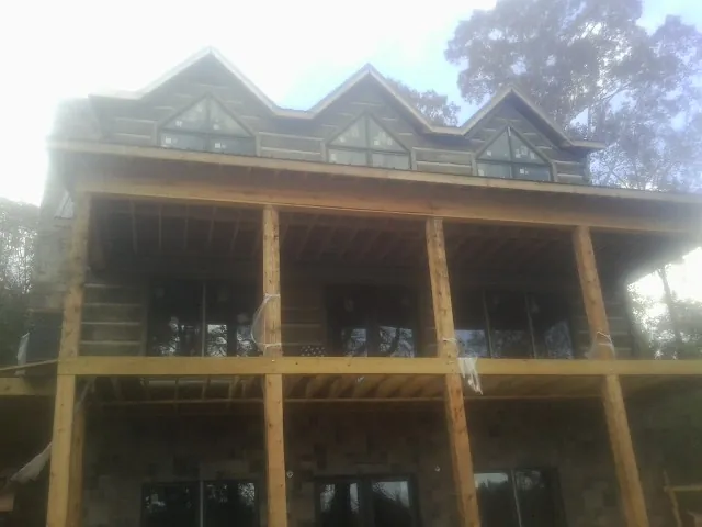 Dormers and porch framing on a large log home under construction — Roof Coating work by our crew in Edgewood