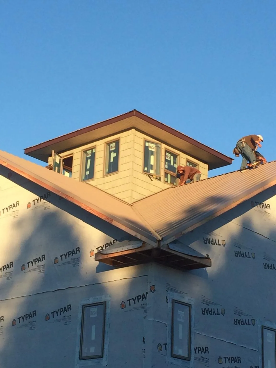 Roofers working around a rooftop cupola on a new metal roof at sunset — Roof Waterproofing in Edgewood by Roofing Brothers